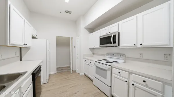a kitchen with granite countertop a sink stove and microwave