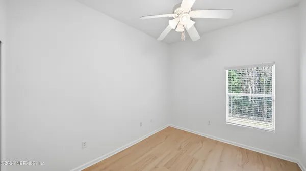 an empty room with a window and a fan