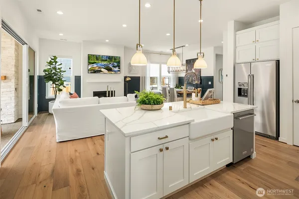 a kitchen with kitchen island granite countertop a sink a refrigerator and a white cabinets