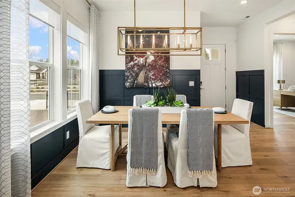 a view of a dining room with furniture a potted plant and wooden floor