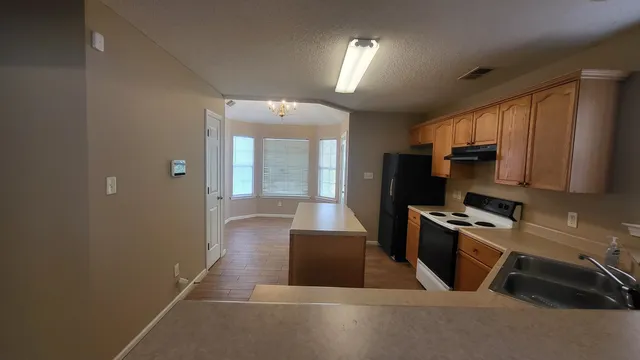 a kitchen with granite countertop a refrigerator and a stove top oven
