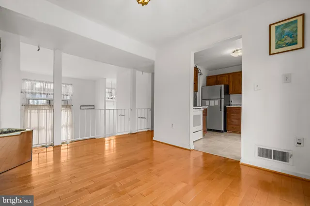 a view of empty room with wooden floor and kitchen
