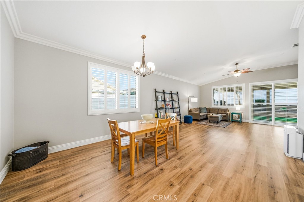 26535 Rim Creek Path, Unit PATHWAY Menifee, CA 92584 - Photo 15 of 50 a dining room with wooden floor a chandelier a wooden table and chairs