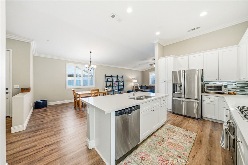 26535 Rim Creek Path, Unit PATHWAY Menifee, CA 92584 - Photo 10 of 50 a kitchen with refrigerator a sink and wooden floor