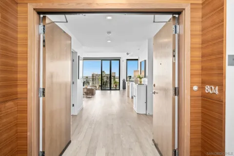 a view of a hallway with wooden floor and a bathroom