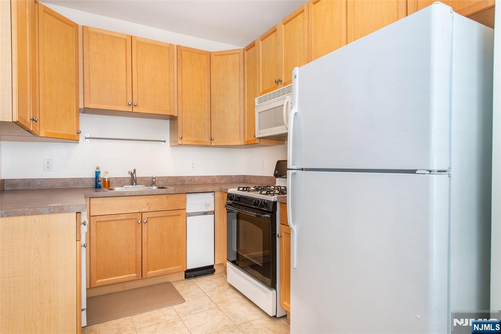 201 Dey Street, Unit 124 Harrison, NJ 07029 - Photo 12 of 26 a kitchen with stainless steel appliances granite countertop a refrigerator and a stove top oven