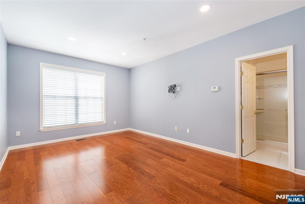 201 Dey Street, Unit 124 Harrison, NJ 07029 - Photo 21 of 26 a view of an empty room with wooden floor and a window