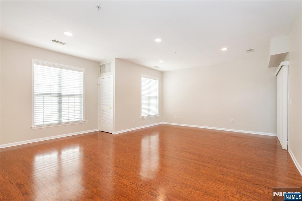 201 Dey Street, Unit 124 Harrison, NJ 07029 - Photo 5 of 26 an empty room with wooden floor and windows