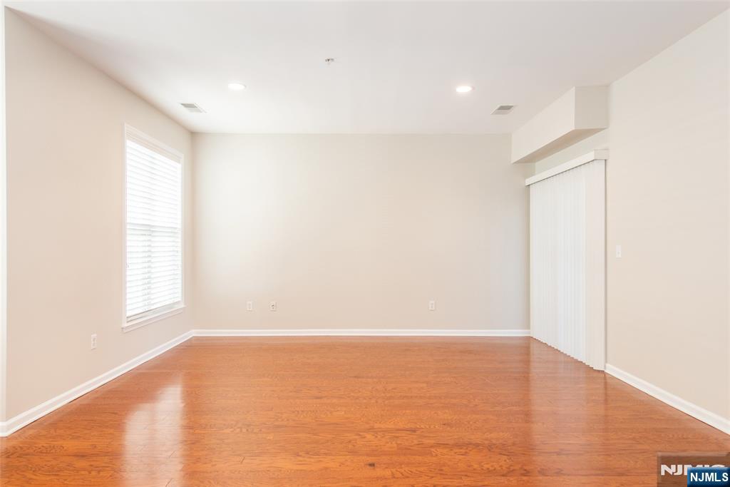 201 Dey Street, Unit 124 Harrison, NJ 07029 - Photo 9 of 26 a view of an empty room with wooden floor and a window