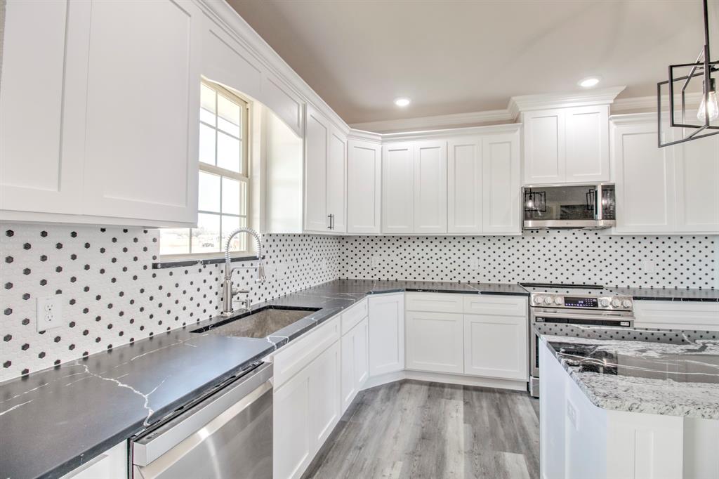 6180 Old Sherman Road Whitesboro, TX 76273 - Photo 9 of 30 a kitchen with granite countertop a sink a stove a microwave and island