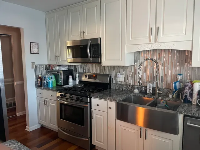 a kitchen with stainless steel appliances granite countertop a stove a sink and a microwave