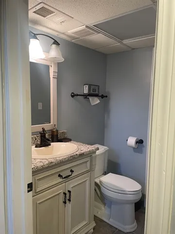 a bathroom with a granite countertop toilet sink and mirror