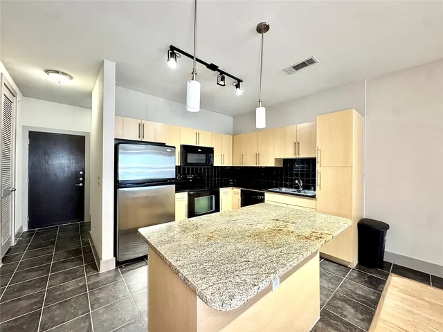 a kitchen with stainless steel appliances kitchen island granite countertop a refrigerator and microwave