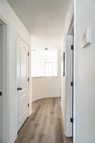 a view of a hallway with wooden floor and closet area
