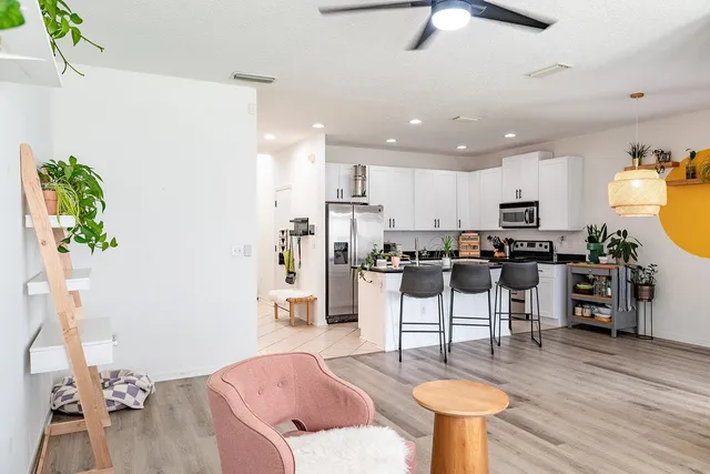 a living room with stainless steel appliances furniture a rug kitchen view and a chandelier