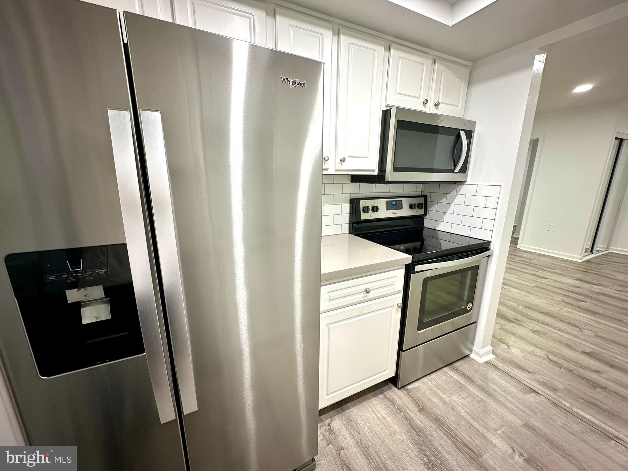18334 Streamside Drive, Unit 202 Gaithersburg, MD 20879 - Photo 21 of 61 a kitchen with white cabinets and stainless steel appliances