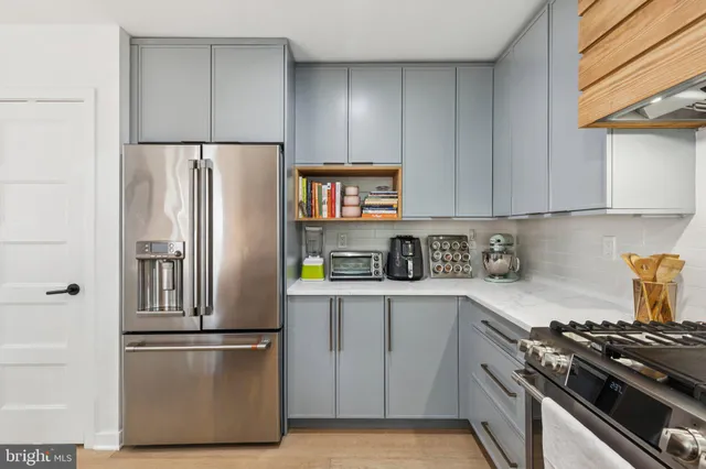 a kitchen with stainless steel appliances a refrigerator a sink and white cabinets