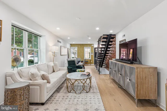 a living room with furniture a flat screen tv and a floor to ceiling window