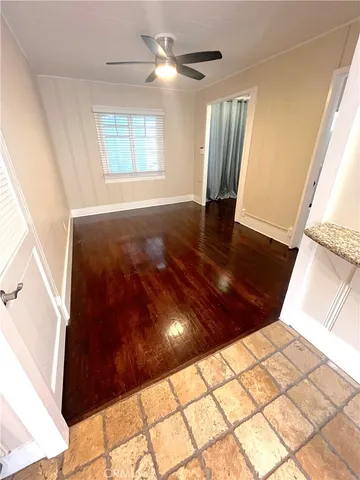a view of empty room with wooden floor and fan