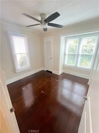 a view of an empty room with a window and wooden floor