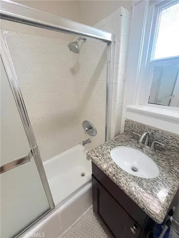 a bathroom with a granite countertop sink a mirror and a bathtub