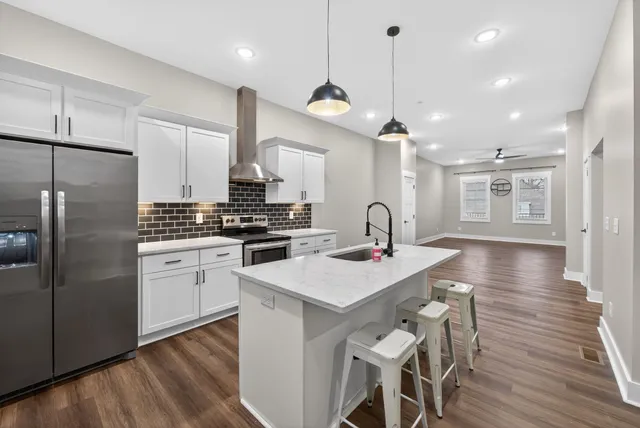a kitchen with stainless steel appliances kitchen island a wooden floor and white cabinets