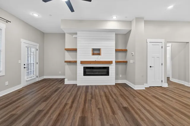 an empty room with wooden floor a fireplace and windows