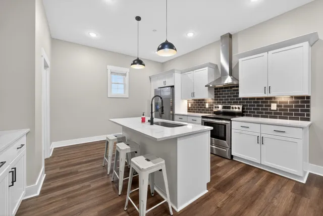 a kitchen with wooden floor a sink stainless steel appliances and cabinets