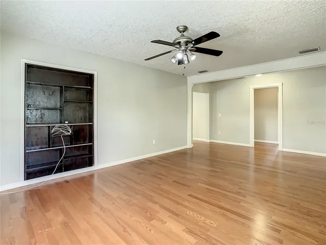 an empty room with wooden floor & windows