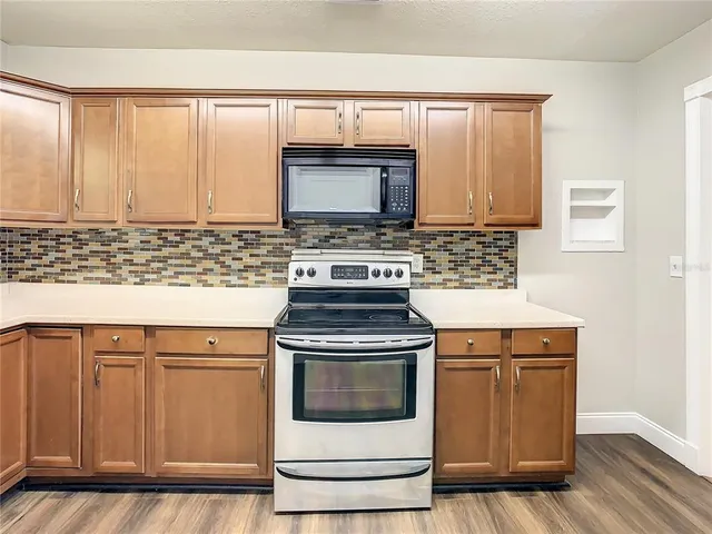 an empty room with wooden floor closet and windows