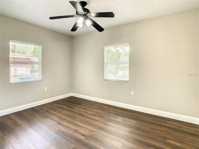 an empty room with wooden floor and windows