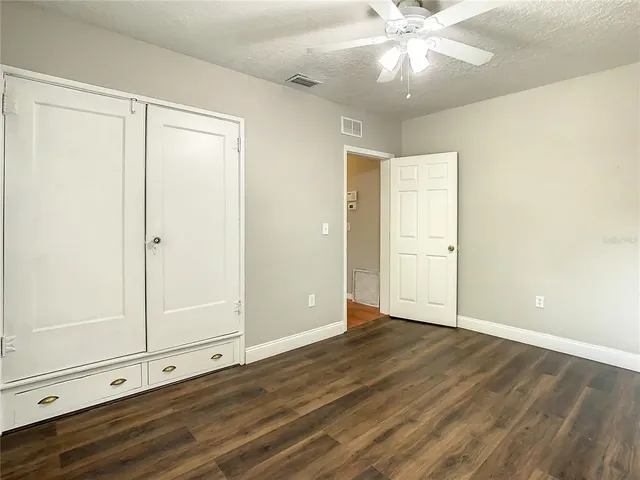 a view of white house with a big yard and large trees