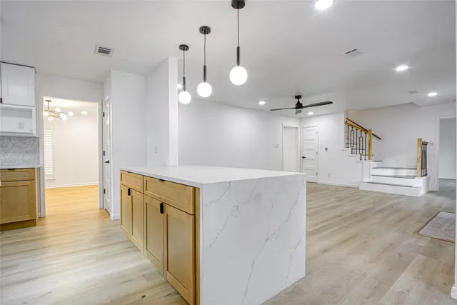 an open kitchen with wooden floor and large windows