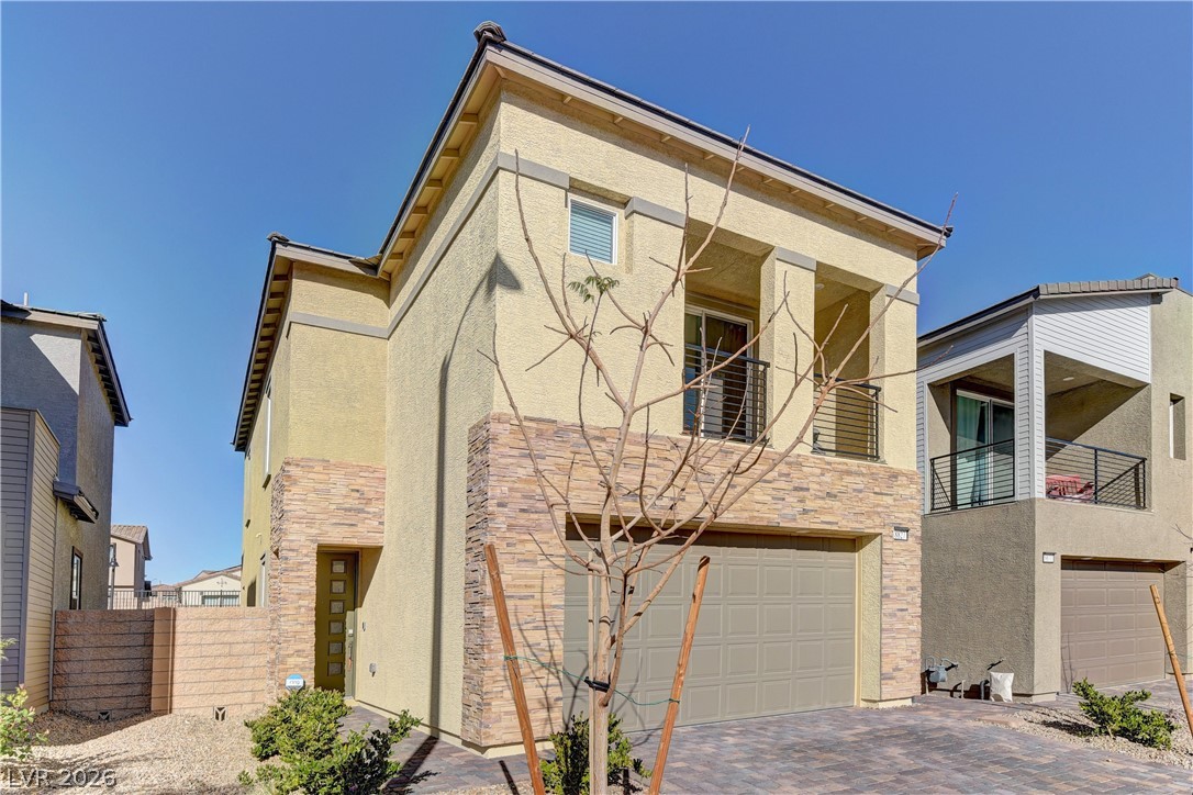 8827 Roadrunner Ravine Street Las Vegas, NV 89166 - Photo 1 of 17 View of front of house featuring a balcony, stucco siding, an attached garage, and stone siding