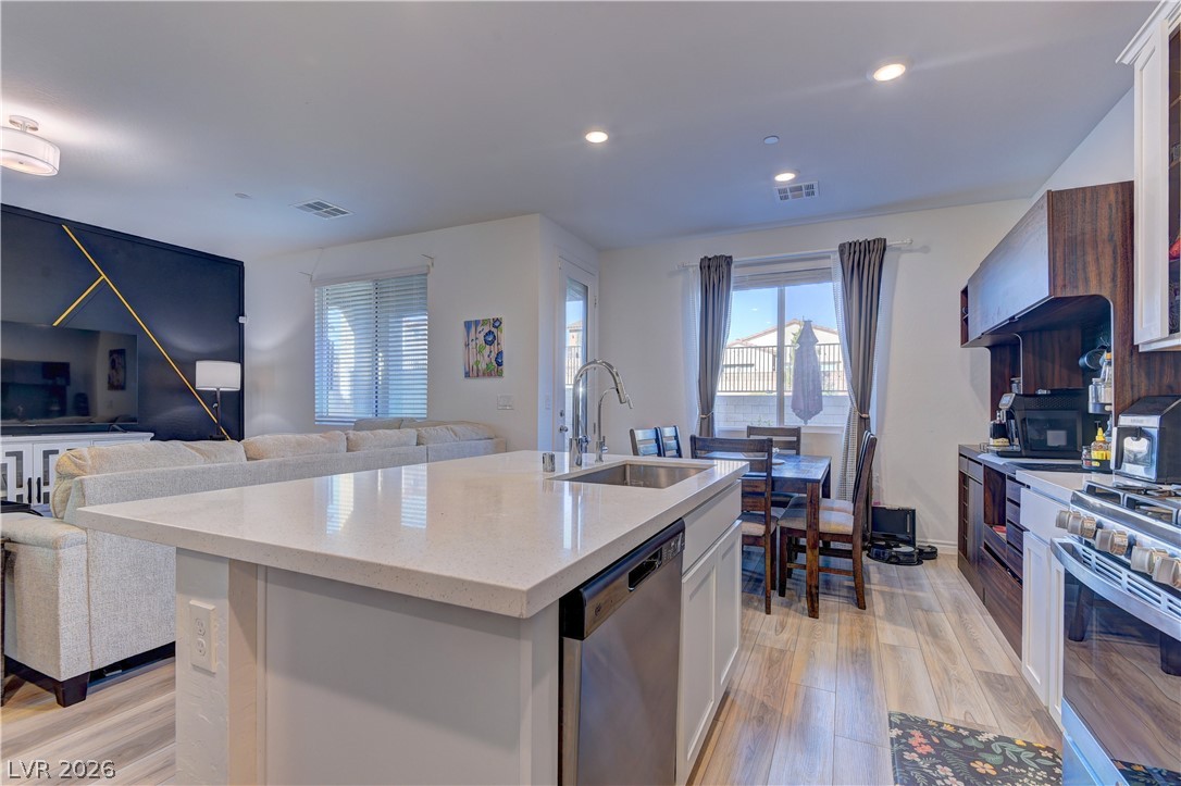 8827 Roadrunner Ravine Street Las Vegas, NV 89166 - Photo 17 of 17 Kitchen with open floor plan, stainless steel appliances, light stone countertops, light wood-style flooring, and a center island with sink