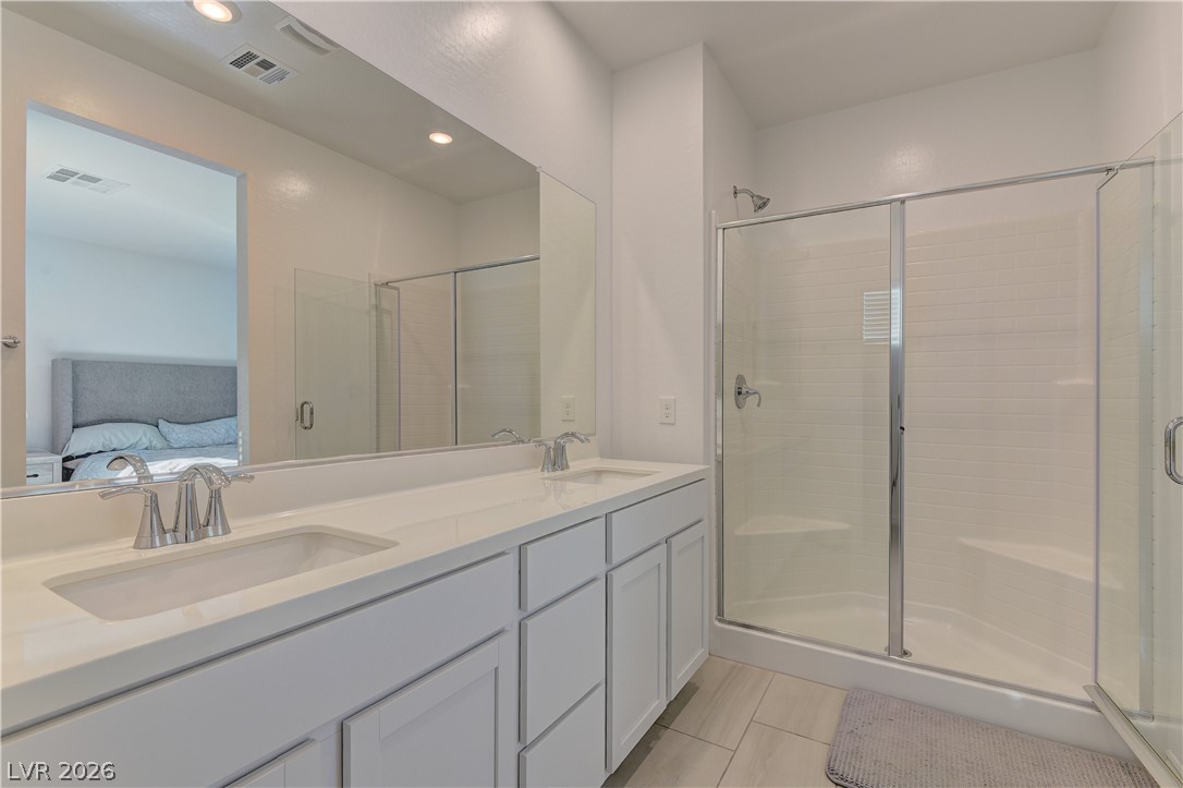 8827 Roadrunner Ravine Street Las Vegas, NV 89166 - Photo 9 of 17 Ensuite bathroom with double vanity, a stall shower, light tile patterned floors, and recessed lighting