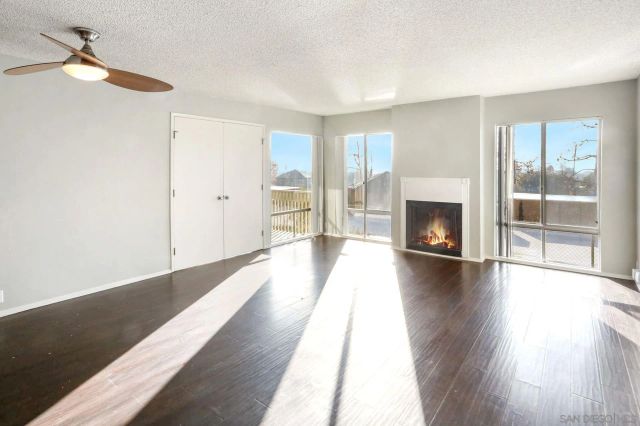 a view of an empty room with wooden floor fireplace and a window