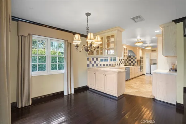 a view of a kitchen with kitchen island a window wooden floor and stainless steel appliances