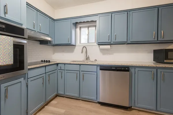 a kitchen with stainless steel appliances granite countertop white cabinets sink and dishwasher
