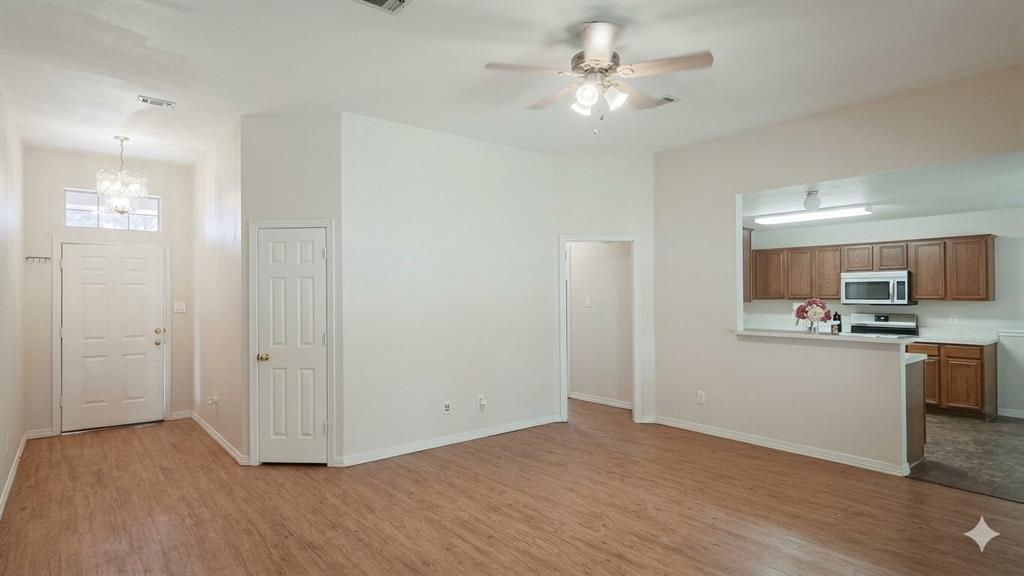 211 Vista Ridge Drive Venus, TX 76084 - Photo 6 of 24 Open-concept living area with wood-finish flooring, a contemporary ceiling fan, and a pass-through window to the kitchen