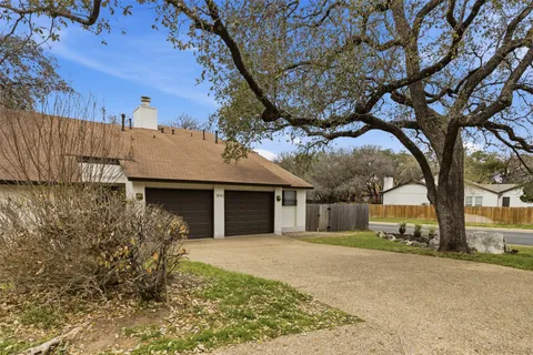 a front view of a house with a yard and large tree