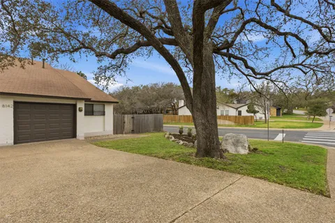 a front view of a house with garden and trees