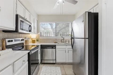 a kitchen with stainless steel appliances granite countertop a refrigerator a sink and white cabinets