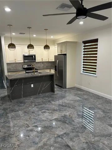 a kitchen with kitchen island a counter top space a sink and appliances