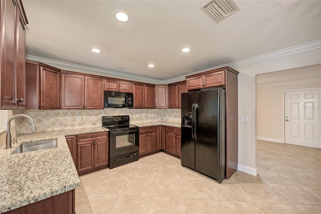 1330 Georgetowne Circle Sarasota, FL 34232 - Photo 14 of 46 a kitchen with granite countertop stainless steel appliances a refrigerator and a sink