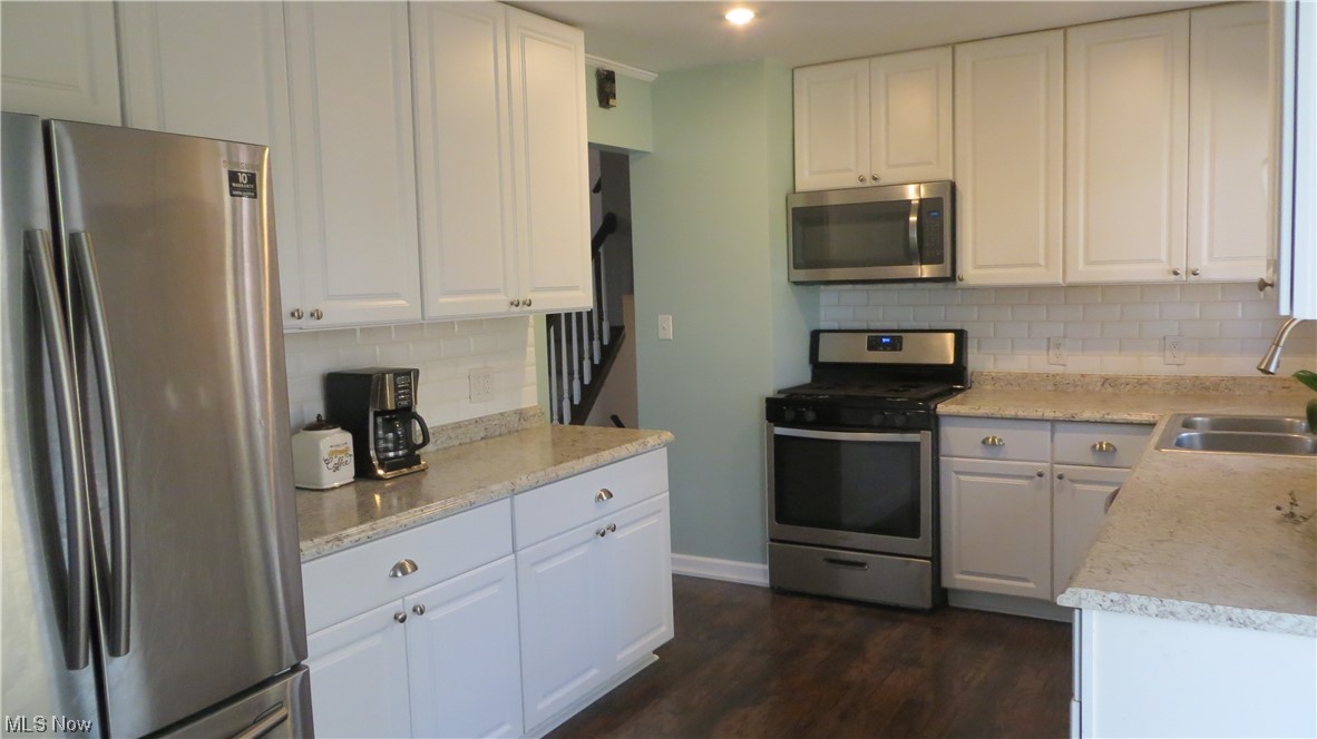 6490 Elmdale Road Cleveland, OH 44130 - Photo 7 of 17 Kitchen with dark hardwood / wood-style floors, sink, appliances with stainless steel finishes, backsplash, and white cabinetry