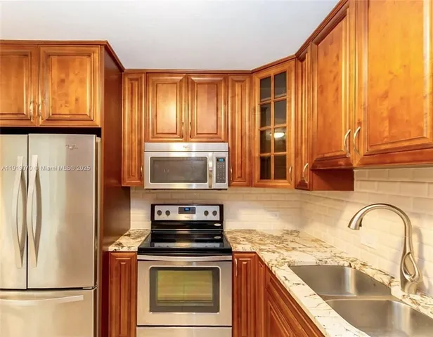 a kitchen with granite countertop a refrigerator and a sink