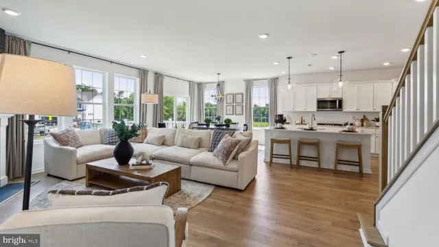a living room with furniture kitchen area and a wooden floor