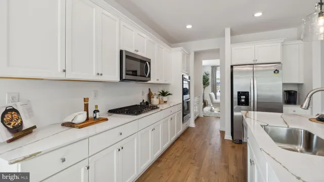 a kitchen with granite countertop a sink stainless steel appliances and white cabinets
