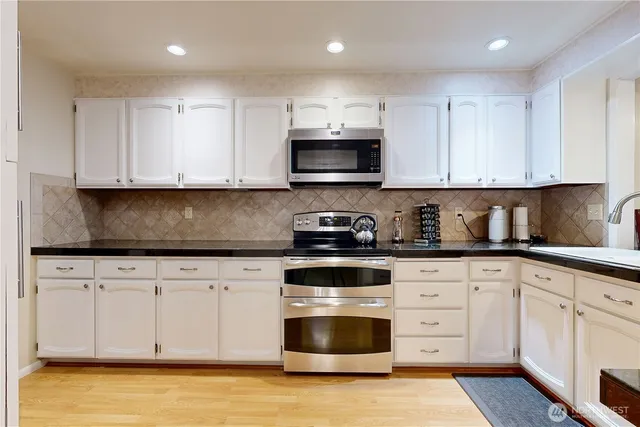 a kitchen with granite countertop white cabinets and stainless steel appliances